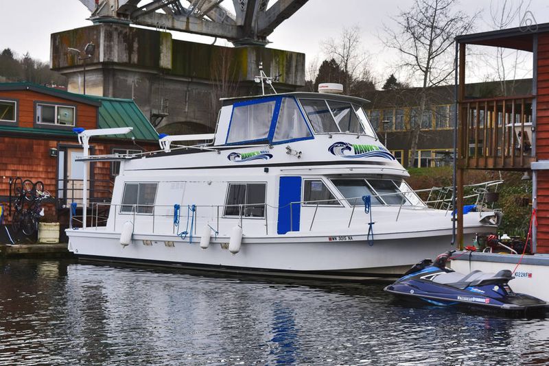 A white boat with a large cabin below and Seahawks-themed details